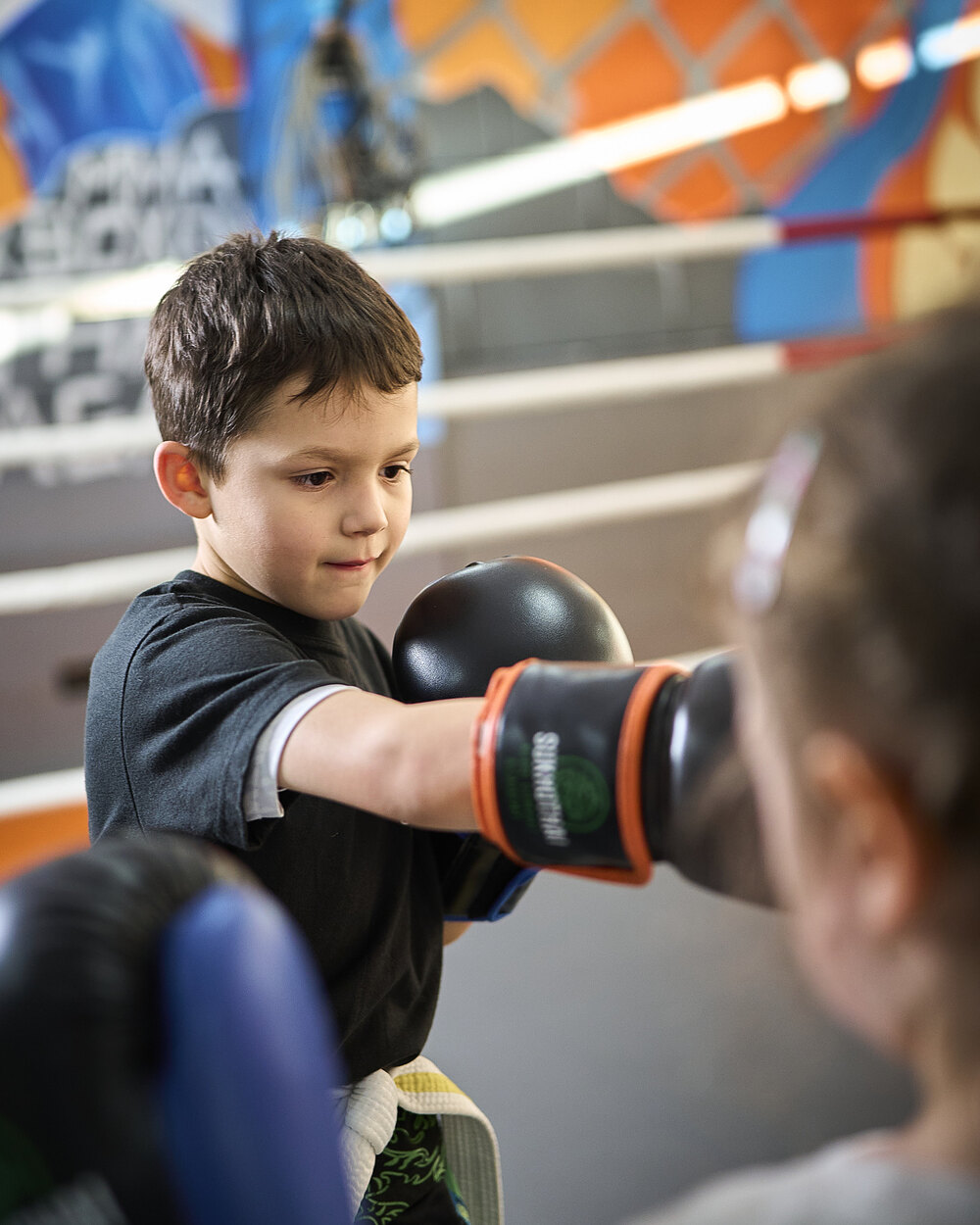 Ein Junge der Power Kids streckt konzentriert den Handschuh zu seiner Partnerin — geübt wird zu zweit, im Ring der Halle in Lahr.